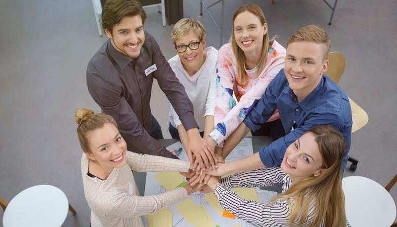 Équipe intergénérationnelle réunie autour d’un projet de travail collaboratif, symbolisant la cohésion et le management bienveillant en entreprise.