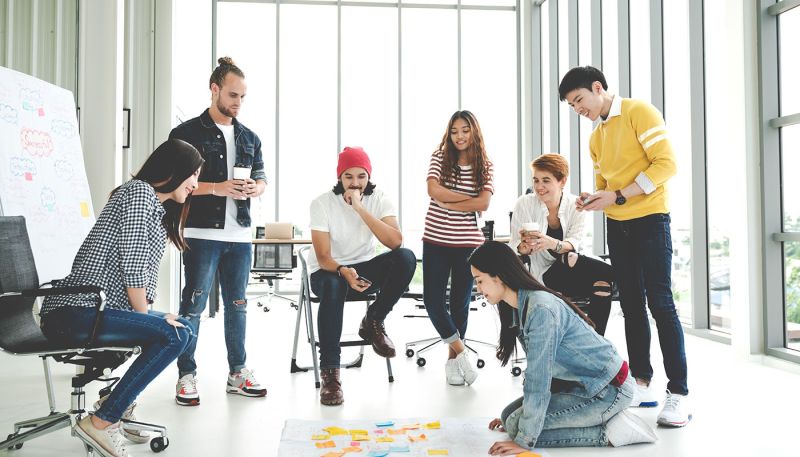 Équipe de jeunes professionnels collaborant lors d’une journée de cohésion en entreprise, organisée dans un espace lumineux et moderne.
